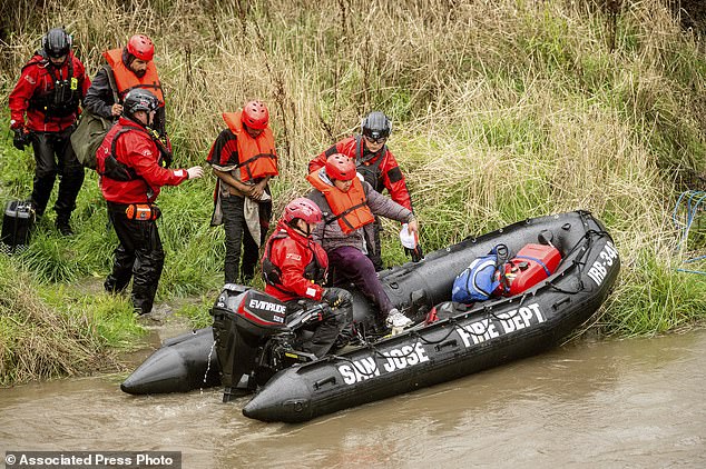 Search and rescue workers evacuate men from a homeless camp surrounded by floodwaters from the Guadalupe River