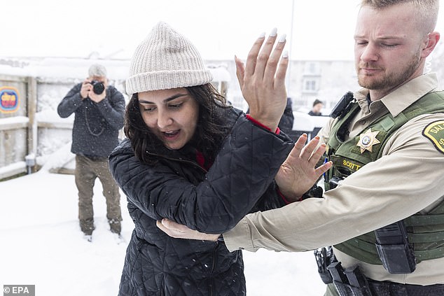 Dallas County Police (R) remove a climate protester (C) who yelled at Republican presidential candidate and former South Carolina Governor Nikki Haley after a campaign rally at Mickey's Irish Pub in Waukee, Iowa, January 9