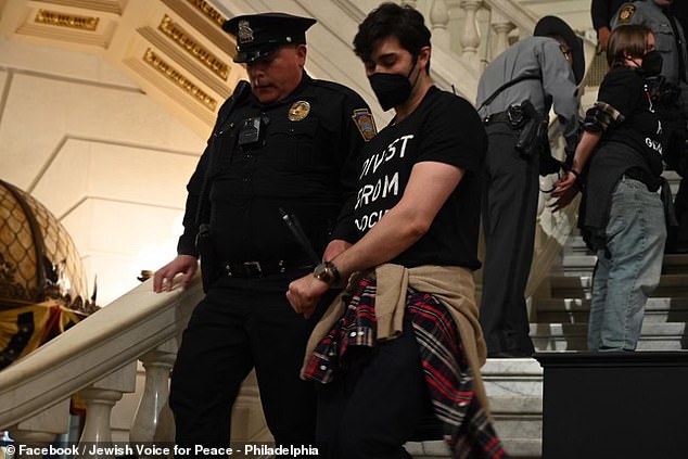 Protesters were led away by police with their hands tied with zip ties