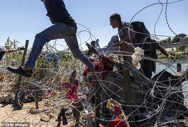 On September 28, migrants are seen jumping over barbed wire in Eagle Pass, Texas.  Mayorkos said the 