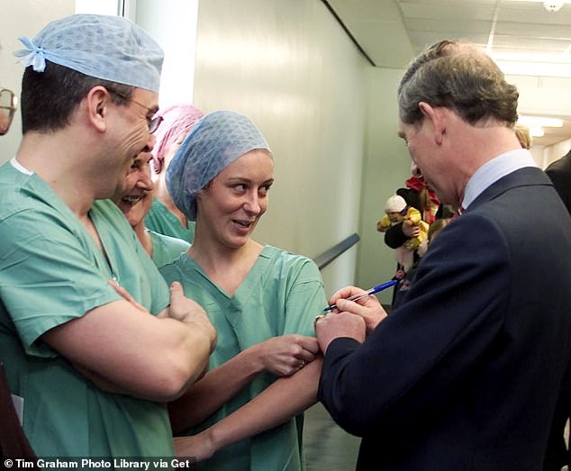 Nurse Karla Graham smiles as Charles writes his signature on her hospital gown in the liver cancer ward at University Hospital in Liverpool in 2002