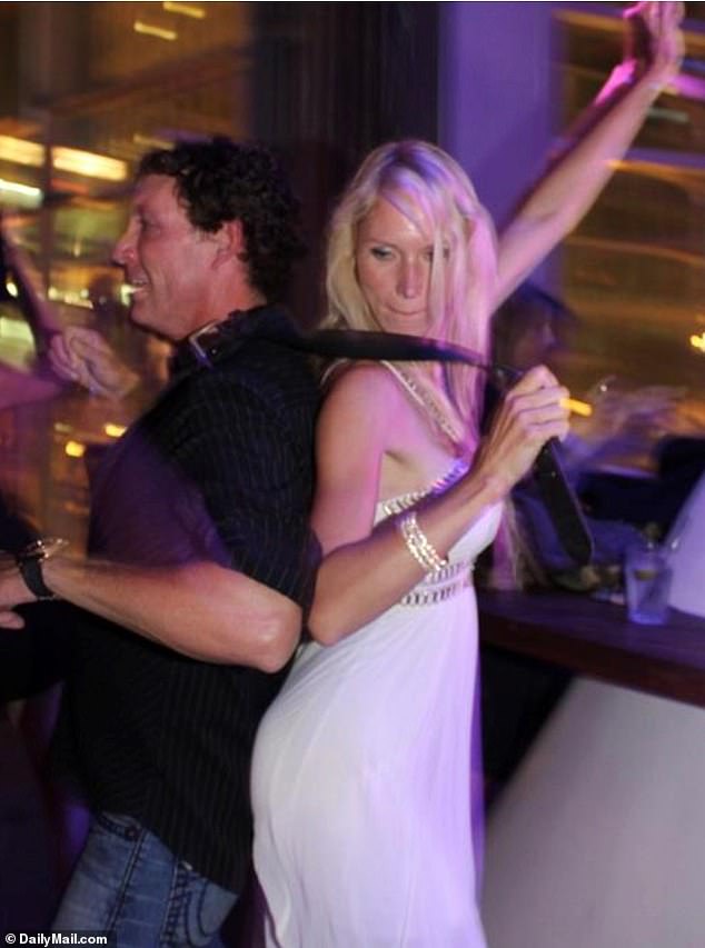 Tatyana holds a leash around husband Mark Remley's neck and leads him around a party