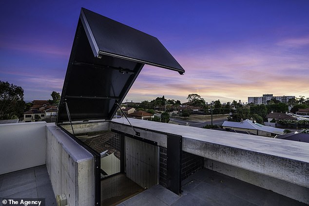 At the top of a three-story floating staircase is a hatch that opens to reveal a huge roof terrace with stunning views of the city skyline