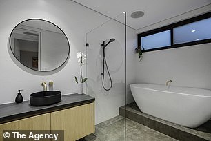 The shared bathroom has a monochromatic color palette and a raised freestanding bath