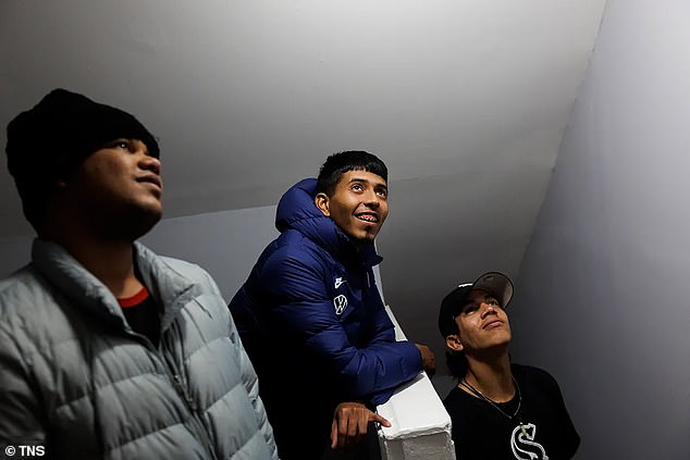 Robinson Covis, 25, from left, Abel Gonzalez, 27, and Daniel Antonio Ruiz, 21, all from Venezuela, watch as Amatore installs a smoke detector