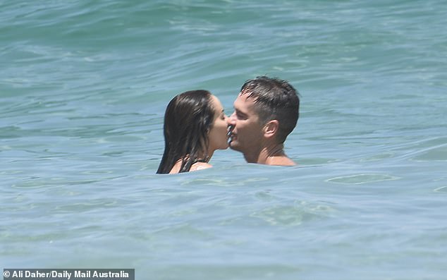 The couple exchange several passionate kisses as they jump around in the sea, causing onlookers to admire their open, affectionate behavior.