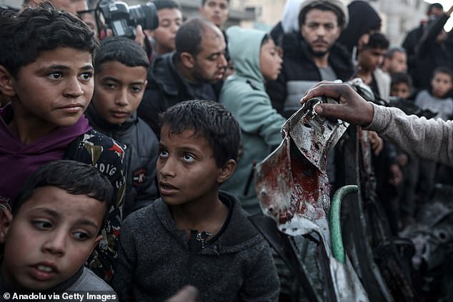 Palestinians inspect a destroyed car after the Israeli attacks in Rafah