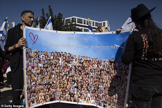 People hold a sign with photos of people who died on October 7.  Hamas deadly attack on the 'Nova' party during a memorial event held by families of victims