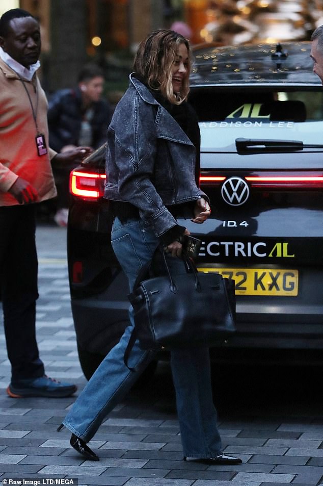 She played with her hair while holding two black bags and completed her look with shiny black boots