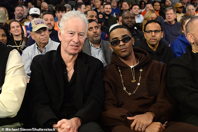 John McEnroe looked sharp in a jet black jacket paired with a matching button-up shirt, while Myles Truitt stayed comfortable in a brown hoodie during the game.