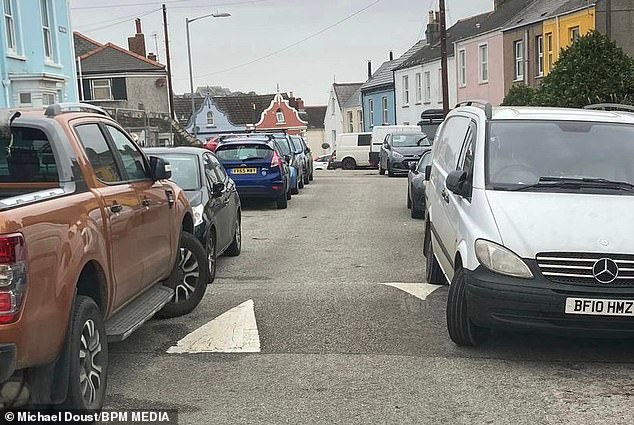 If motorists park partially on the sidewalk, this is often due to the narrow road.  Placing at least two wheels on the sidewalk creates more space for other vehicles to drive safely through tight spaces.  However, this is often at the expense of pedestrians