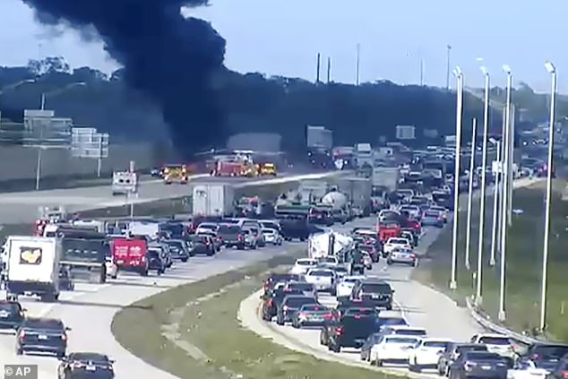 Black smoke billows from the wreckage as cars are stuck in traffic for hours