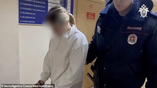 Agafonova is led to the police station in handcuffs.  She is accused of 'desecration of a cemetery' and 'cynical actions that disregard the norms of morality', as well as the 'rehabilitation of Nazism'.