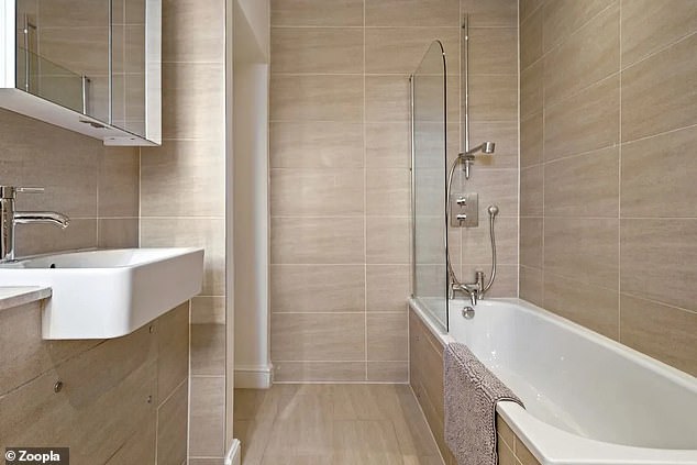 The modern bathroom has floor to ceiling tiles and a modern white bathroom