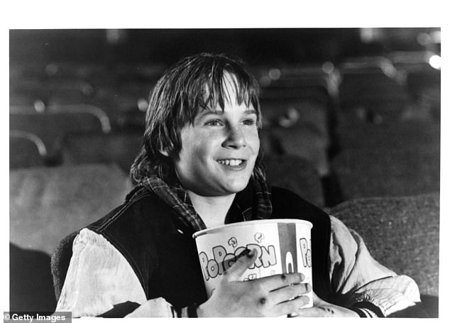 Austin O'Brien eats popcorn at the cinema in a scene from the film Last Action Hero, 1993