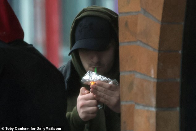 A drug user openly smokes a substance from tin toils in downtown Portland