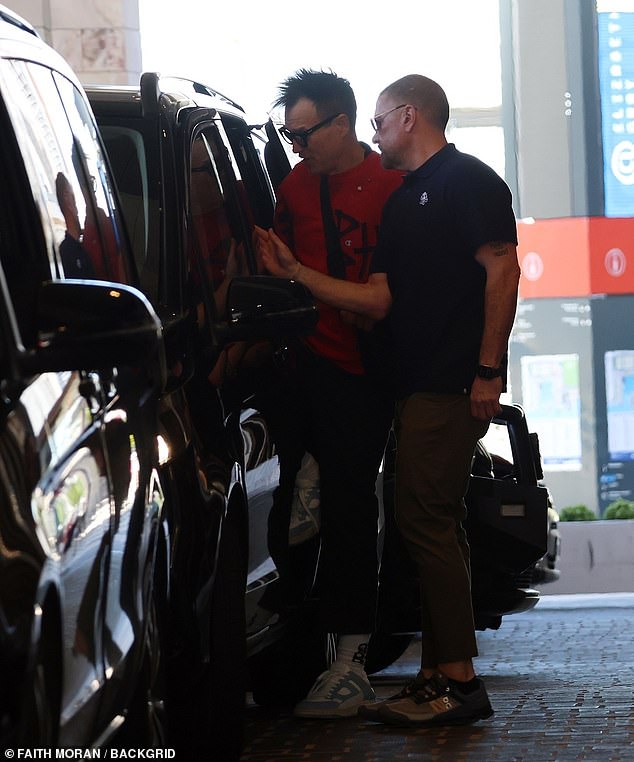 Carrying a black crossbody bag across his torso, the bassist donned his usual black-rimmed glasses and a pair of white sneakers.