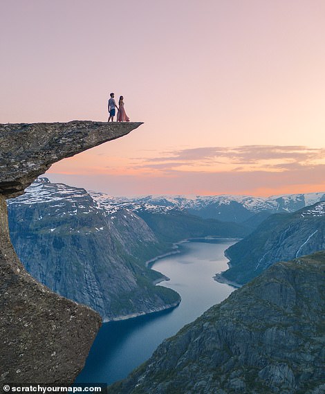 The pair are standing on top of Trolltunga.  One of the most amazing rock formations in Norway, 'floating' 700 meters above Lake Ringedalsvatnet