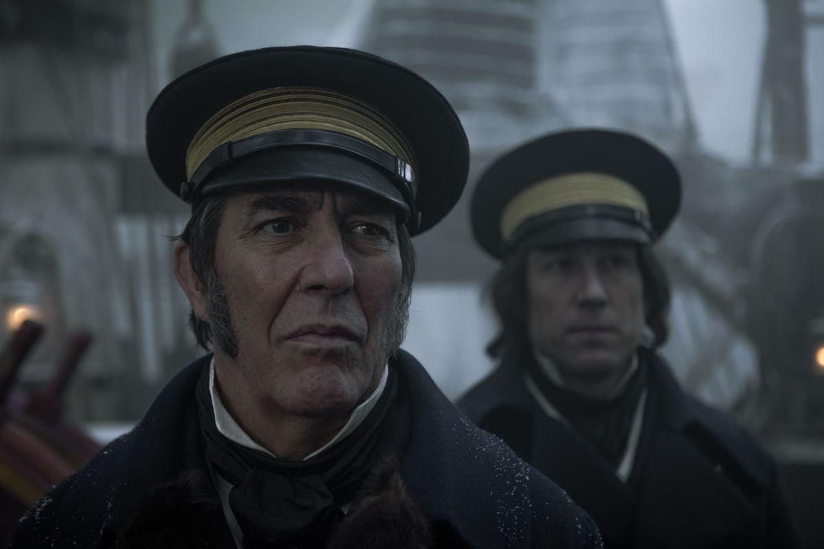 Close-up shot of two men wearing captain hats on board a ship.