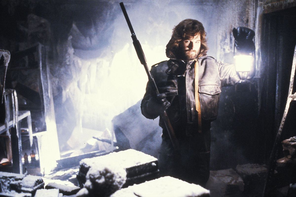 Kurt Russell holds up a lantern in a freezing room