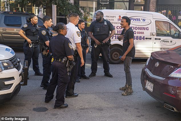 A man, right, is surrounded by three units of New York Police Department officers as they try to calm the man down on October 3, 2023 in New York City.  The agitated man claimed he and his car had been offensive to an inspection