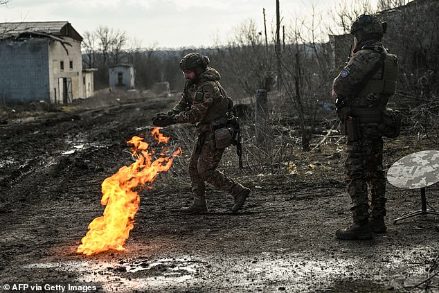 Ukrainian soldiers light a fire with gunpowder to get warm near the city of Bakhmut