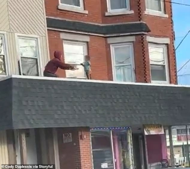 The man is seen reaching out to the baby just before picking him up and bringing him back through the open window