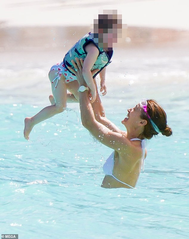 The mother of three was seen happily playing in the ocean with her daughter during the family vacation