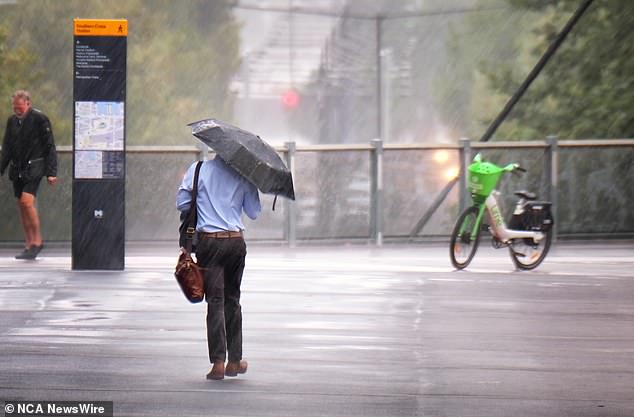 Meanwhile, parts of Melbourne were hit by heavy rain on Tuesday (Photo: A commuter takes shelter from the rain)