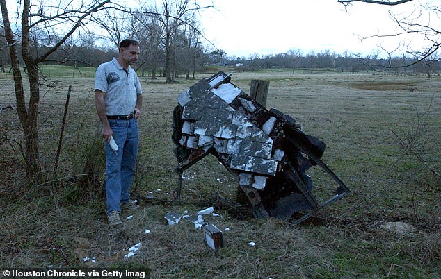 Mac Powell stands next to what he believes is the suspected damaged left wing of the fallen space shuttle Columbia, on his property in Nacogdoches County, Texas in 2003