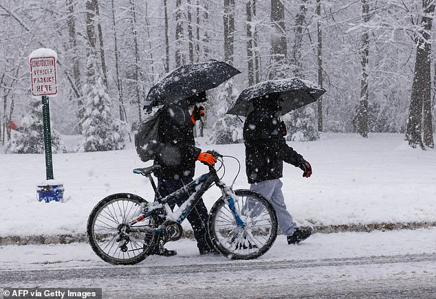 A man pushes a bicycle through the snow in New York.  Winter weather warnings have been issued across the region.