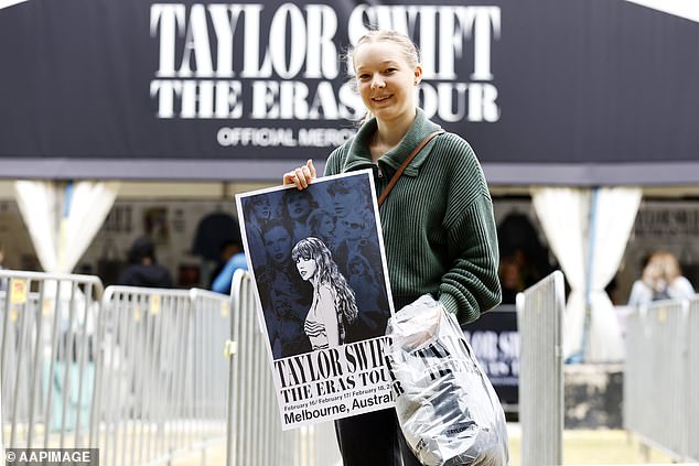 Meanwhile, eager Swifties are already queuing at the MCG to get their hands on official Taylor Swift merchandise, days before the star's first show on Friday.  (Image: a Swiftie with an official tour poster)