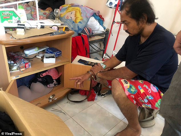 Songchai poses with his bras, pants and pajamas which appear to be hung and stored in cupboards in his apartment