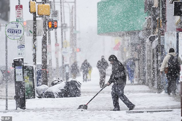 A person clears a sidewalk during a winter snowstorm in Philadelphia on Tuesday