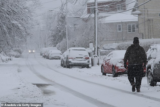 A man walks along a snow-covered road during a snowfall in Hudson County, New Jersey, on Tuesday