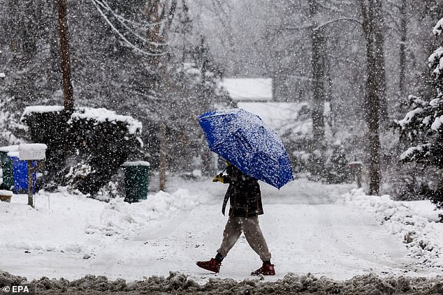 A pedestrian walks along the road amid heavy Tuesday snowfall in Attleboro, Massachusetts