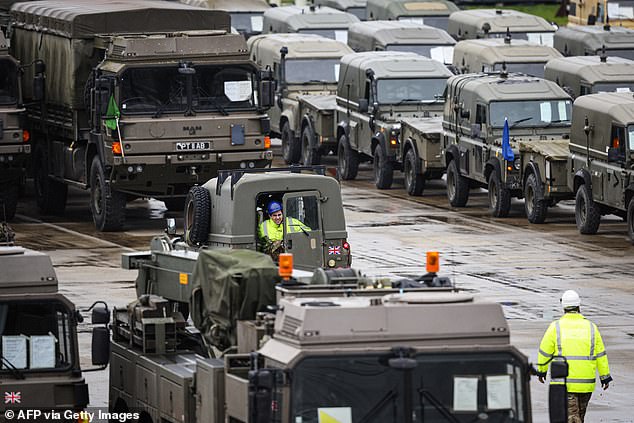 Military vehicles, including trucks and support vehicles, are loaded onto freighters bound for Europe