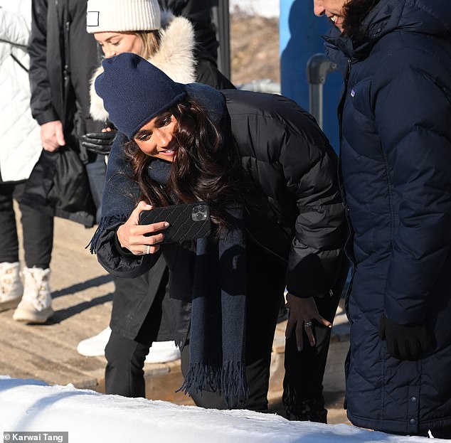The mother-of-two dressed in a black puffer jacket, black jeans and a navy blue hat and scarf, while also showing off a glimpse of her large engagement ring
