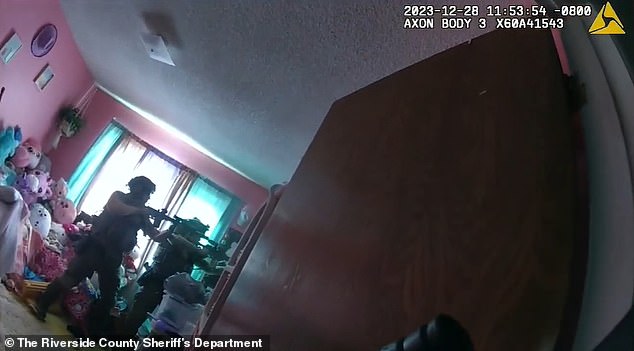 Two officers are seen pointing their guns at Gambill after discovering him upstairs in the closet