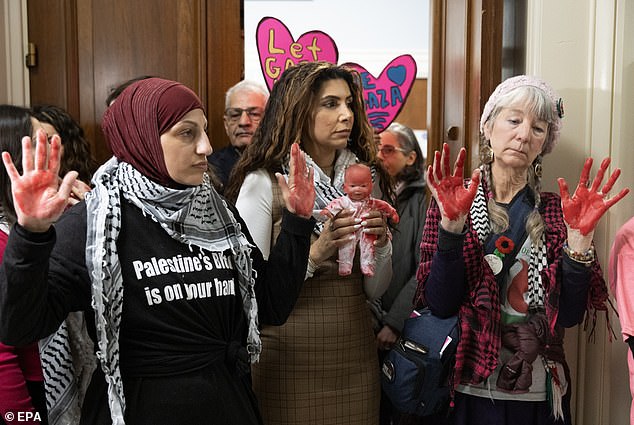 Women show their red hands and red paint on a baby doll during their protest on Capitol Hill