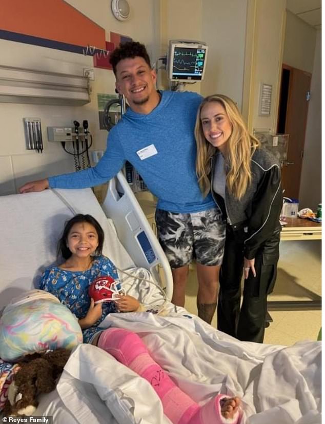 The NFL star and his wife posed Wednesday with the two girls who underwent surgery after being shot in the leg during the parade.  Eight-year-old Melia, whose forehead was marked with ashes for Lent, grins as she holds a mini Chiefs football helmet