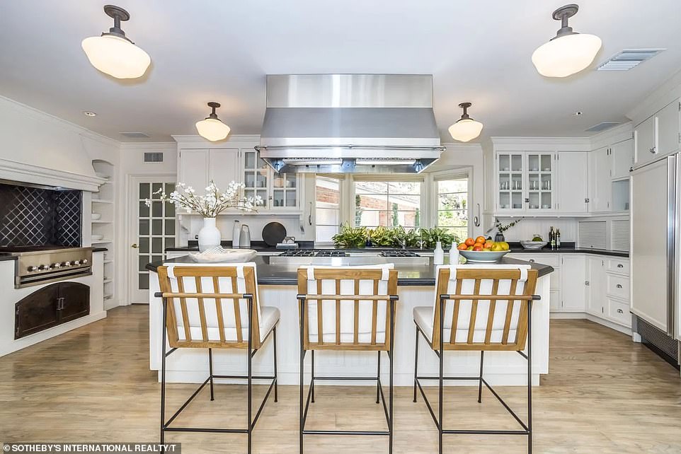 The kitchen includes white wooden cabinets, a large island in the center and an indoor barbecue for a unique touch