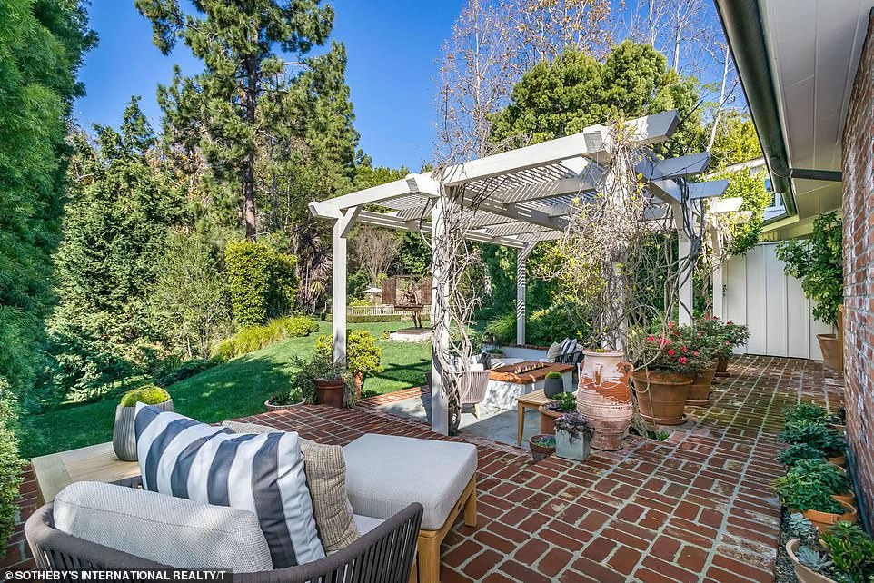 The brick patio provides plenty of space for comfortable furniture such as soft sofas and tables, while potted plants line the walls of the house