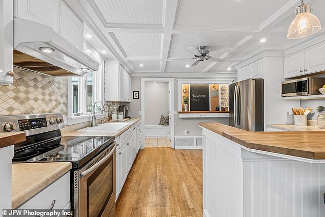 The updated kitchen features hardwood floors and coffered ceilings, giving the space a dramatic and grand look