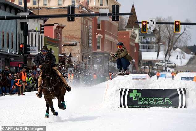 Rider Carl Gomez races down Harrison Avenue as skier Ben Southworth makes a jump during the 75th annual Leadville SkiJoring weekend competition in Colorado on March 4, 2023