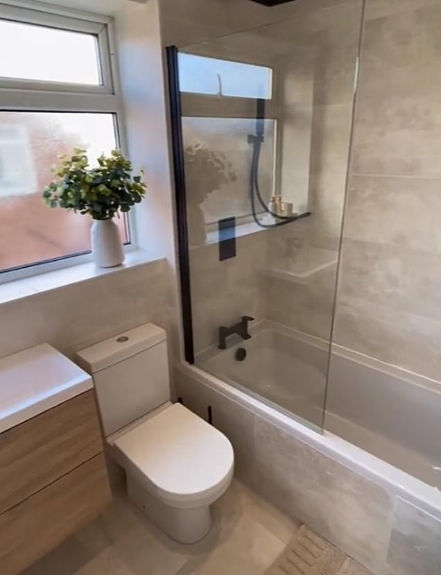 The porcelain, round red sink has been turned into a rectangular vanity, fitted with pinewood panels, while decorative items such as artificial plants in white vases have been placed on the windowsill to add depth and color to the room