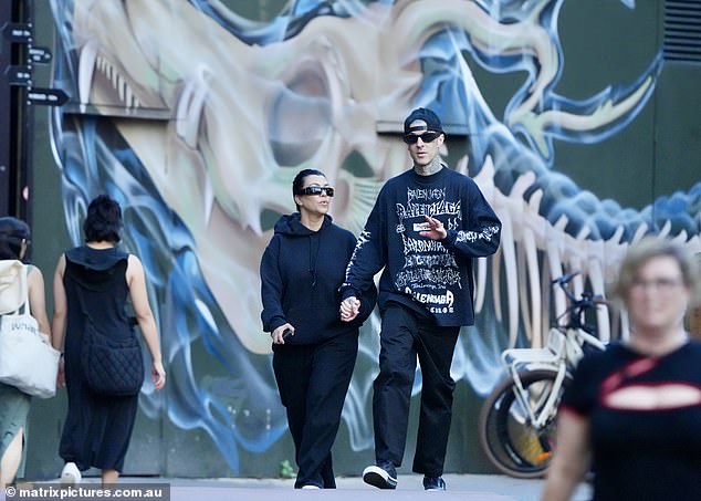 The husband and wife both wore dark shades for the walk, while Travis also wore a backwards black cap