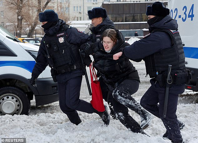 Police officers detain a woman during a rally in memory of Russian opposition leader Alexei Navalny at the Wall of Grief monument