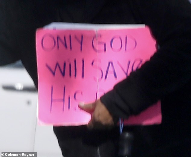 The beggar was carrying a large neon pink sign that read 'Only God will save his people'