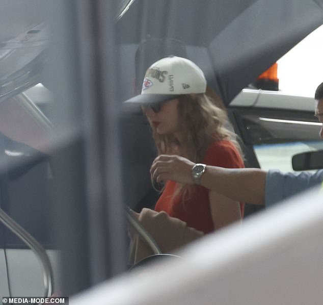 The hitmaker was spotted aboard her private jet in Melbourne earlier today wearing a Kansas City Chiefs Super Bowl LVIII Champs baseball cap in tribute to her boyfriend Travis Kelce (pictured)